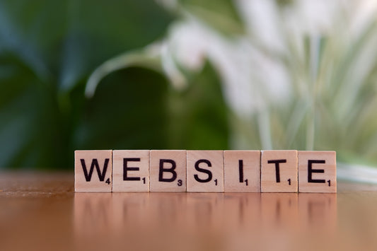 A wooden block spelling the word website on a table
